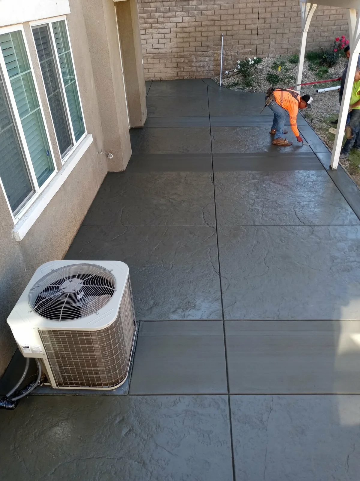 Stamped concrete patio being finished beside a home