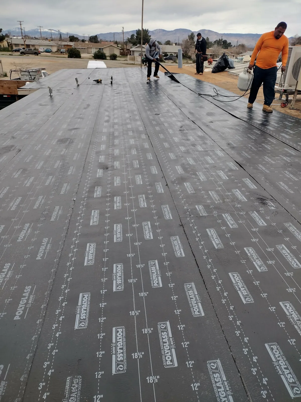 Crew installing a torch-down flat roofing system
